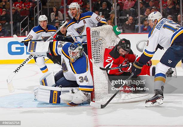 Jake Allen of the St. Louis Blues defends his net as Jay Bouwmeester checks Kyle Palmieri of the New Jersey Devils during the game at the Prudential...