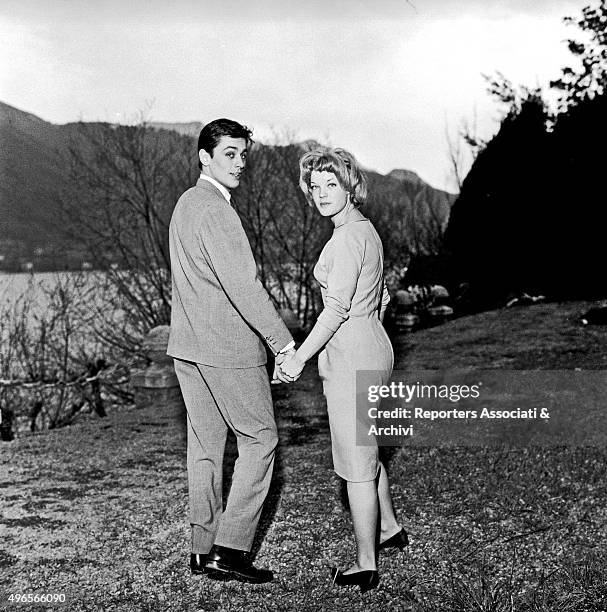 French actor Alain Delon walking hand in hand with German actress Romy Schneider at their engagement party in Vico Morcote, a village of Canto of...