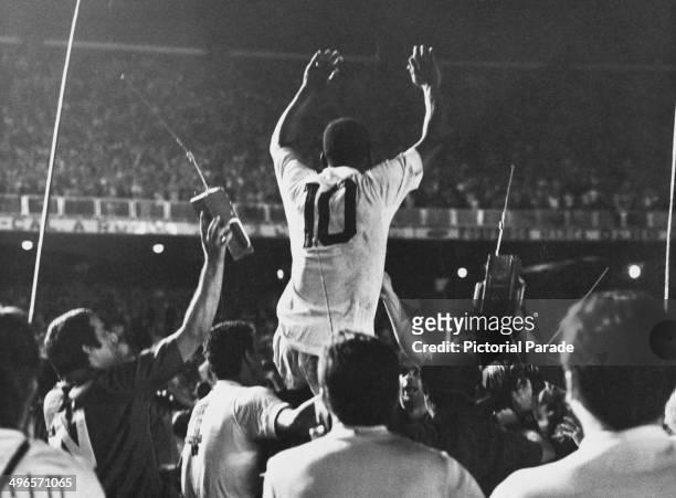 Pele is lifted up by his Santos team mates after scoring the 1,000th goal of his career during a game against Vasco da Gama at the Maracana Stadium,...
