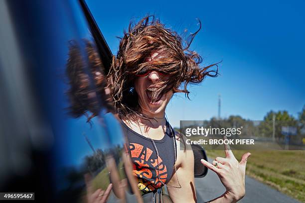 young woman hanging out car window - spensieratezza foto e immagini stock