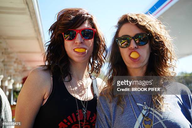two young women eating oranges - mundraum stock-fotos und bilder