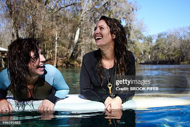 two young women laughing on stand up paddleboard - sup stock pictures, royalty-free photos & images