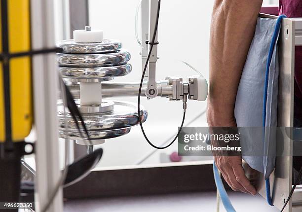 The arm of volunteer Stephan Bernstein is strapped to a cushion beside a mechanical pendulum pain threshold testing machine at the robot collision...