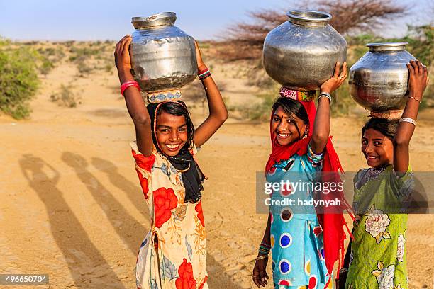 indian young girls carrying on their heads water from well - carrying on head stockfoto's en -beelden