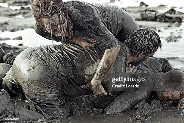 men and woman mud wrestling - mud wrestling stock pictures, royalty-free photos & images