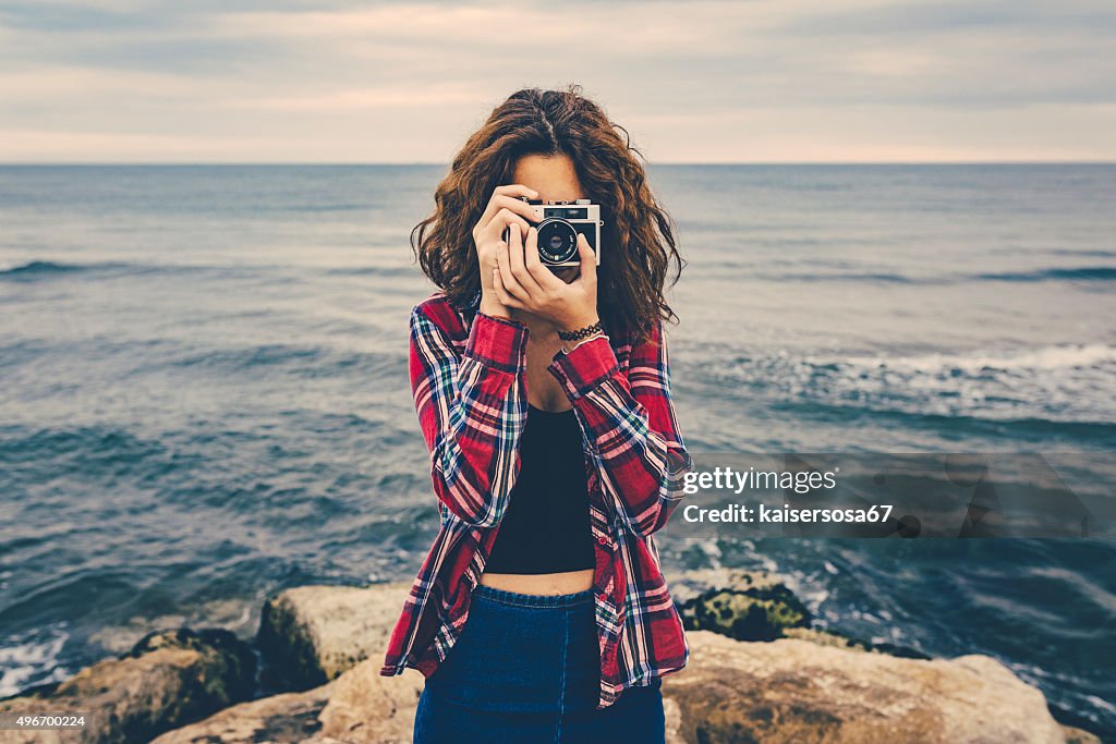 Girl taking a photo at sea with a film camera