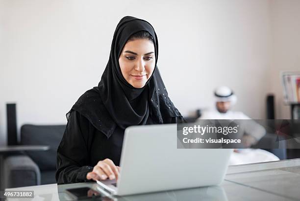 middle eastern woman using computer at home - middle east cool stockfoto's en -beelden