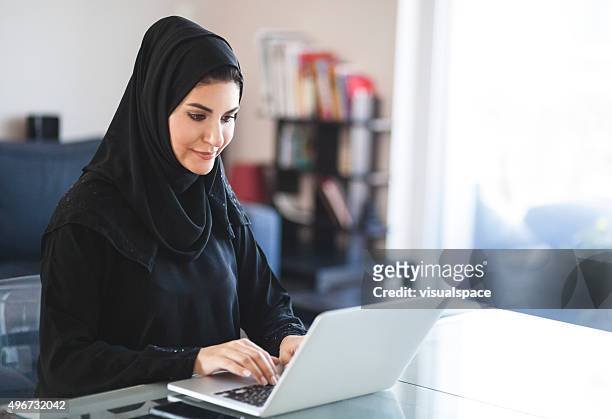 emirati woman working with laptop at home - united arab emirates culture stock pictures, royalty-free photos & images