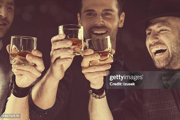 happy elegant men toasting with whiskey - whisky stock pictures, royalty-free photos & images