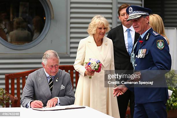 Prince Charles, Prince of Wales and Camilla, Duchess of Cornwall sign a visitors book with Commissioner of Police, Andrew Scipione during a visit to...