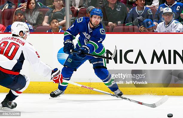 Dan Hamhuis of the Vancouver Canucks shoots the puck past Marcus Johansson of the Washington Capitals during their NHL game at Rogers Arena October...