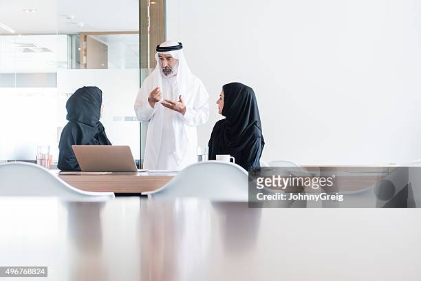 arabische geschäftsmann und frauen, die treffen in modernen büro, dubai - emirati guy using laptop stock-fotos und bilder