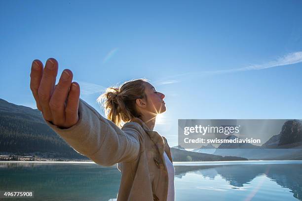 young woman arms outstretched by the lake, sun rising - arms outstretched mountain stock pictures, royalty-free photos & images