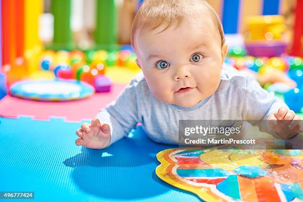 young baby boy playing in his playpen doing tummy time - sensory perception stockfoto's en -beelden