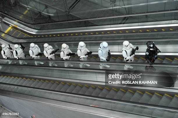 Imperial Stormtroopers and a TIE pilot from the Star Wars film franchise travel up an escalator during a promotional event at the Changi...