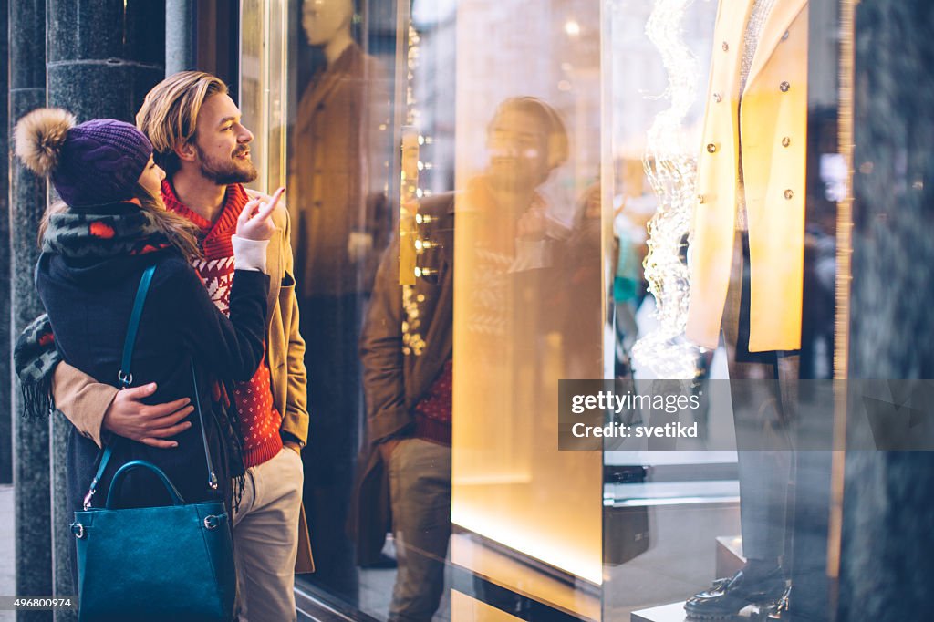 Couple window shopping outdoors in winter city street.