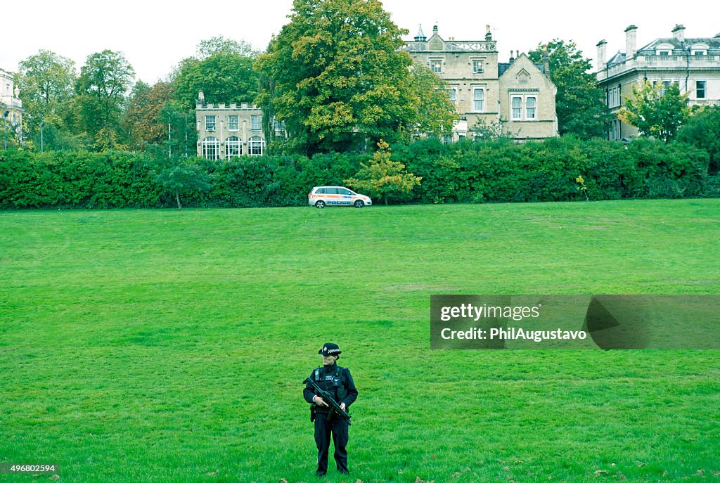 Policewoman guarding field behind embassy row in London UK