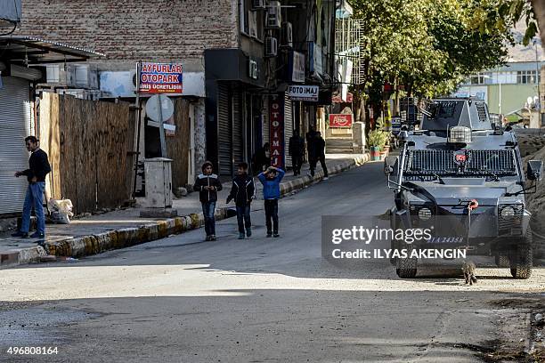 Young boys walk past an armoured police vehicle down an almost empty street in Silvan, southern-eastern Turkey, on November 12 during a curfew...