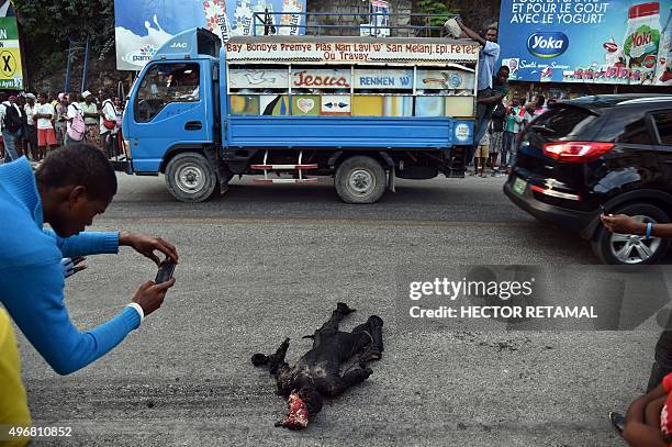 Man takes photos of the burnt body of a man, in the commune of Petion Ville, in Port-au-Prince, on November 12, 2015. The man was burned alive with...