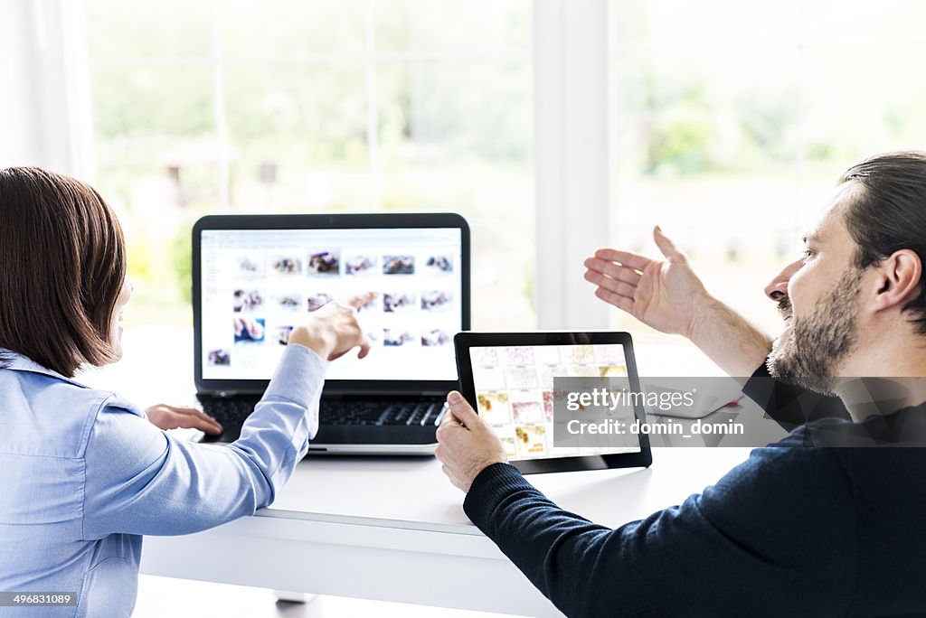 Team choosing images together on laptop and tablet, home office