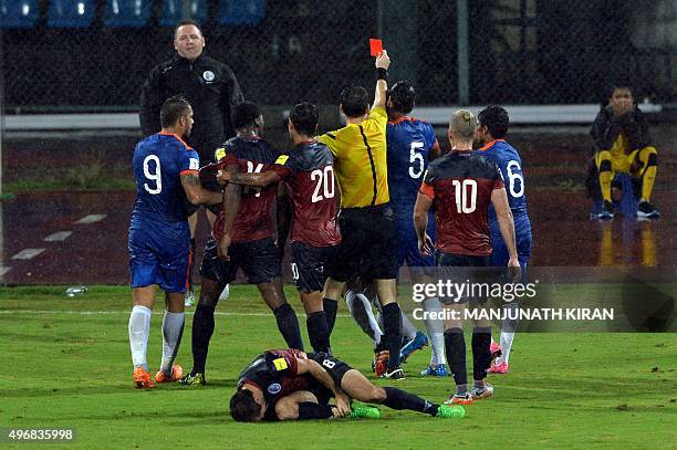 Refree Jarred Gaven Gillett shows the red card to Indian player Pritma Kotal as Guam's mid fielder Justin David cries in pain during the the Asia...