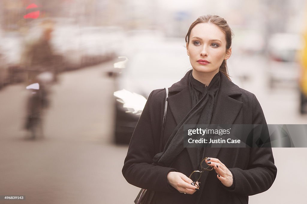 Classy woman holding glasses among the blurry city