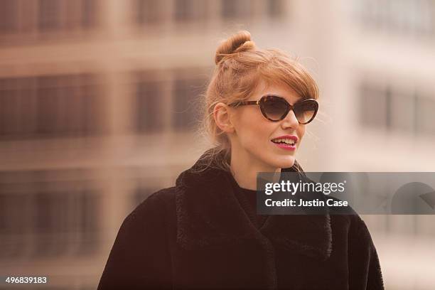 portrait of an elegant woman smiling in the city - haarknoten stock-fotos und bilder