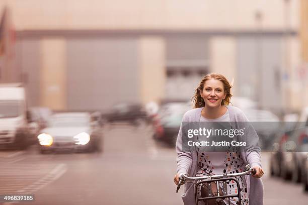 blond woman riding her bike in the city - cycling woman stock-fotos und bilder