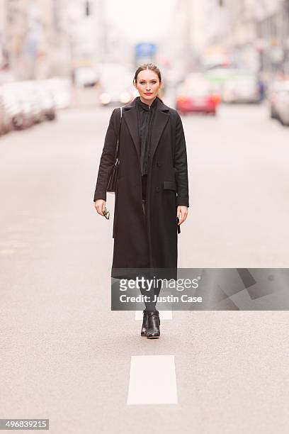 classy business woman standing on a city road - black coat stockfoto's en -beelden