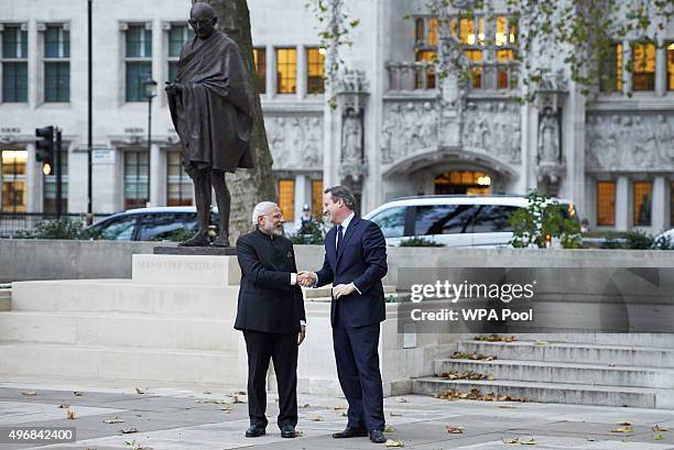 India's Prime Minister Narendra Modi and British Prime Minister David Cameron shake hands in front of a statue of Mahatma Ghandi in Parliament Square...