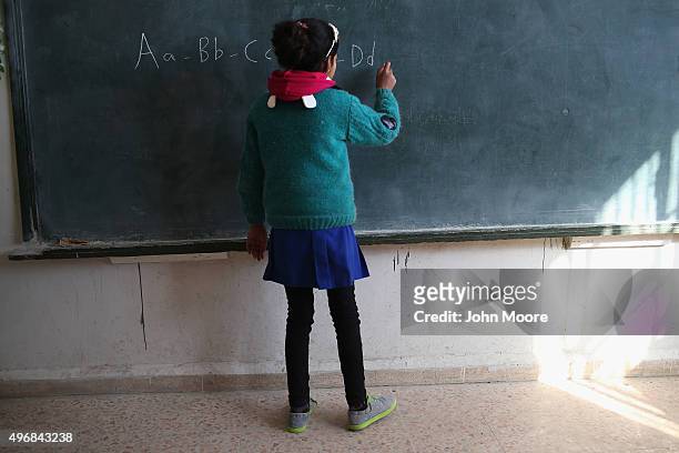 Girl writes the English alphabet during class on November 12, 2015 in Qamishli, Rojava, Syria. With the fall of the Syrian regime and successes...