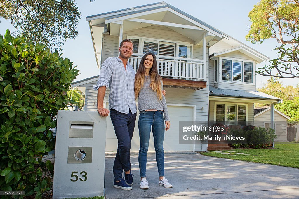 Couple standing by their mailbox in front of new home