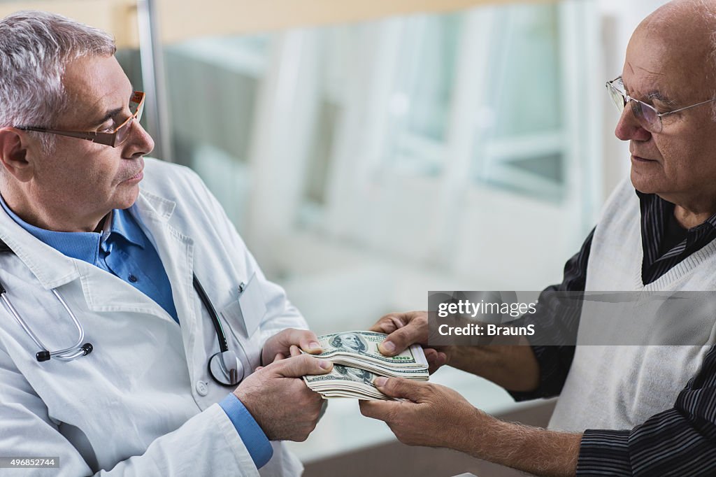 Mature doctor taking a bribe from his senior patient.