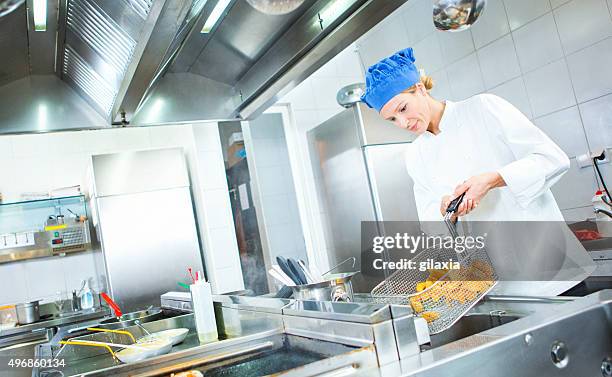 hembra chef friendo papas en el restaurante de cocina. - freidora fotografías e imágenes de stock