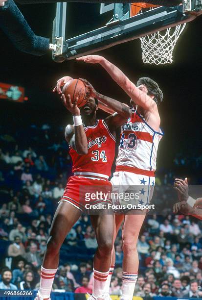 David Greenwood of the Chicago Bulls has his shot challenged by Jeff Ruland of the Washington Bullets during an NBA basketball game circa 1983 at the...