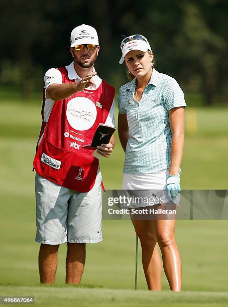 Lexi Thompson of the United States lines up a chip shot on the fourth hole with her caddie Benji Thompson during the first round of the Lorena Ochoa...