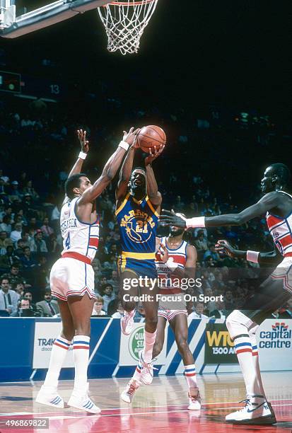 Sleepy Floyd of the Golden State Warriors goes up to shoot over Cliff Robinson of the Washington Bullets during an NBA basketball game circa 1986 at...