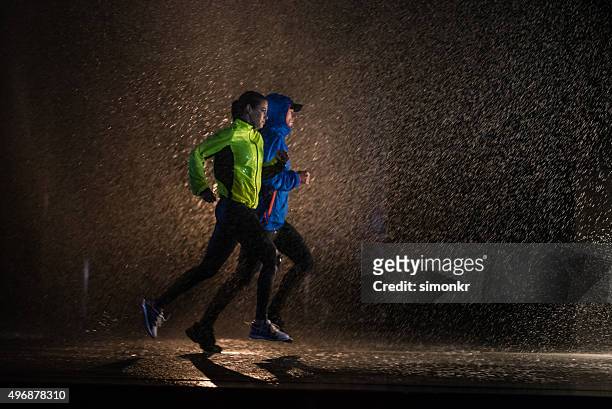 uomo e donna jogging in città - rain foto e immagini stock
