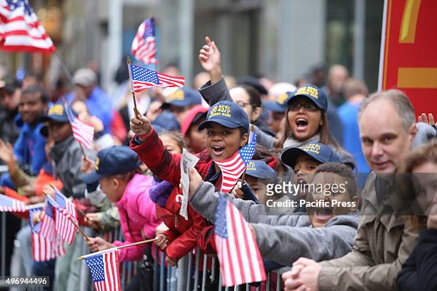 Kids watching parade waving miniature US flags. New York City's Veterans Day was led by the US navy as this year's featured service and grand marshal...