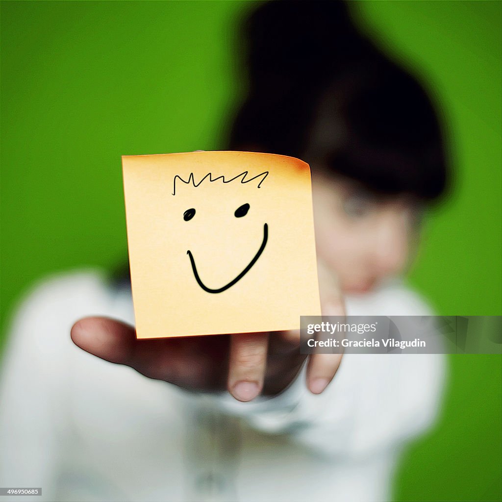 Girl holding yellow note with smily face