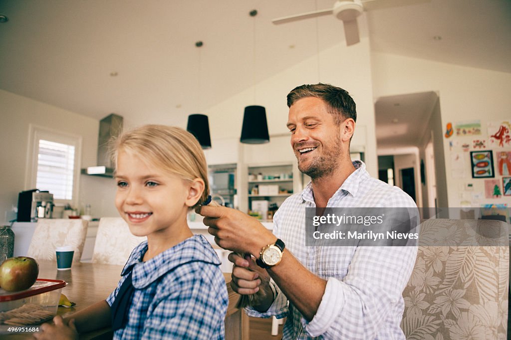 Dad combing daughter's hair for school