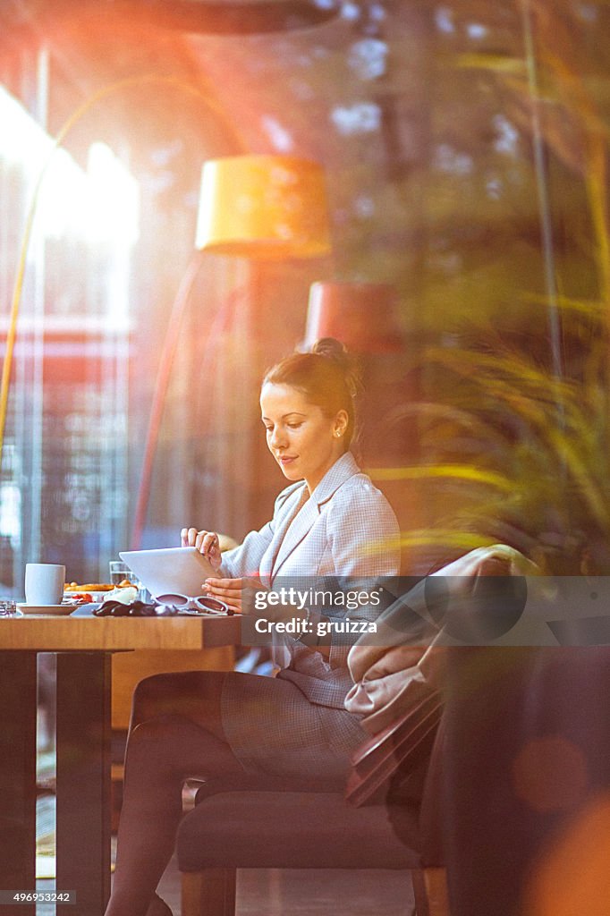 Young businesswoman using her digital tablet at restaurant