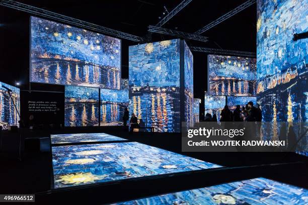 People look at screens displaying part of a painting by Dutch artist Vincent Van Gogh during the official opening of the "Van Gogh Alive" multimedia...