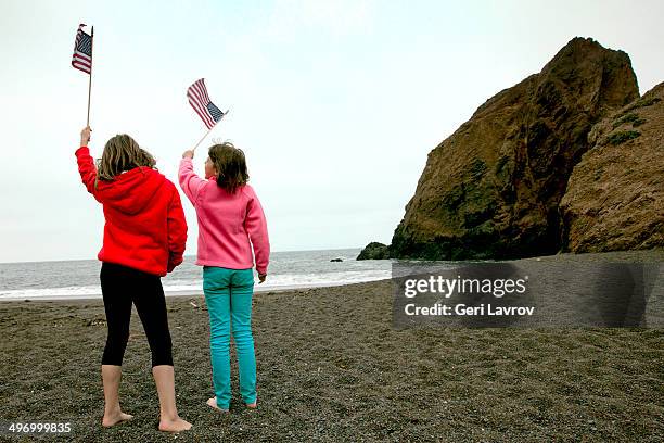 two young girls waving us flags at a beach - girls in leggings stock-fotos und bilder