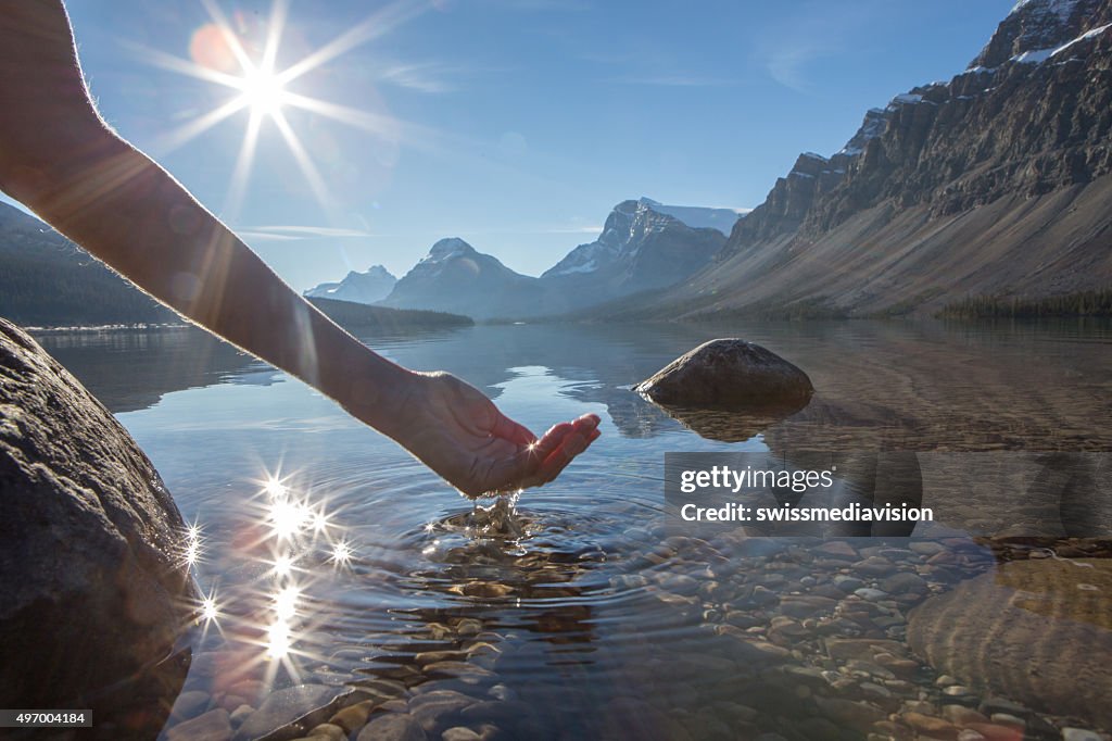 Human hand cupped to catch fresh water from mountain lake