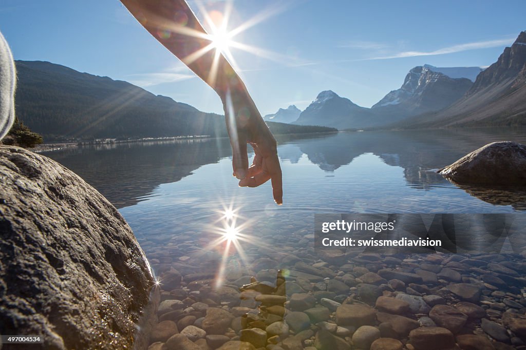 Finger touches surface of mountain lake