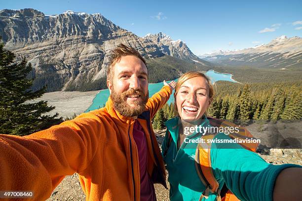 pareja joven caminando alcanza el punto de vista y toma autofoto retrato - banff national park fotografías e imágenes de stock