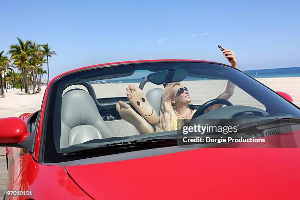 smiley girl in car taking selfie - blonde woman selfie foto e immagini stock
