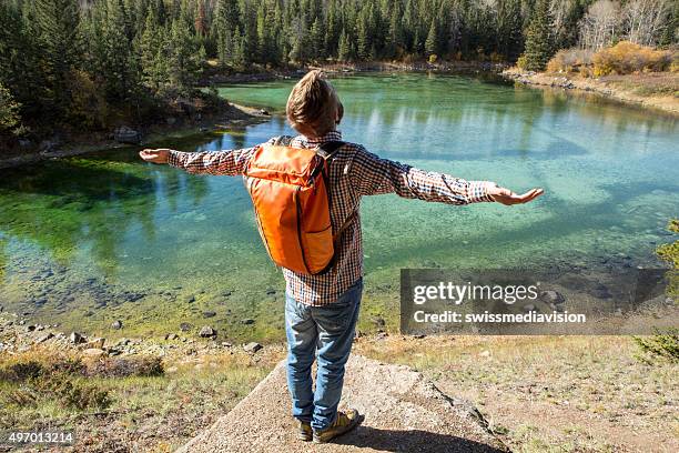 young man hiking reaches a view point, arms outstretched - wide angle stock pictures, royalty-free photos & images