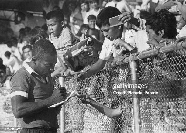 Brazilian footballer Pele signing autographs for young Mexican fans during a training session for the World Cup, 1st June 1970.